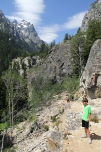 Boy on switchbacks with mountains towering above.